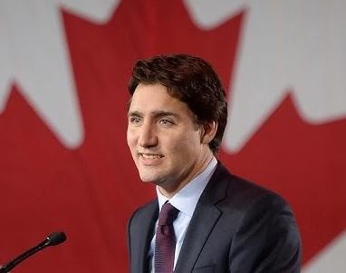 Justin Trudeau w interakcji z ludźmi na publicznym wydarzeniu, uśmiechnięty i przystępny, symbolizujący jego zaangażowanie w kwestie społeczne.