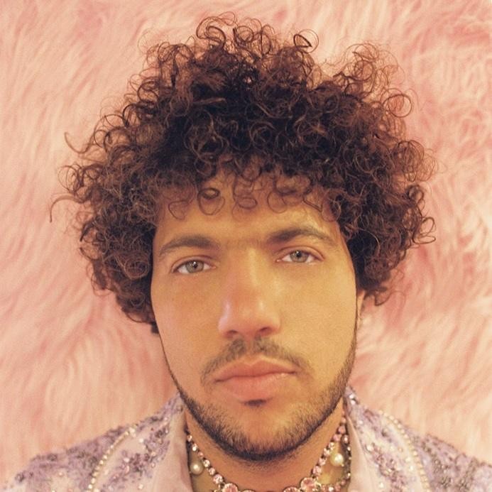 Benny Blanco podczas pracy w studiu nagraniowym, otoczony sprzętem muzycznym, co symbolizuje jego rolę jako producenta i artysty.