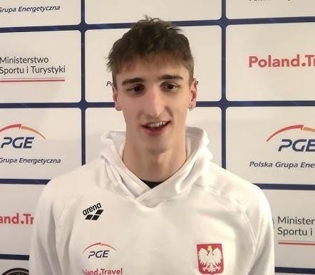 Ksawery Masiuk pływający stylem grzbietowym, symbolizujący jego treningi w Teksasie i połączenie kariery sportowej z edukacją.