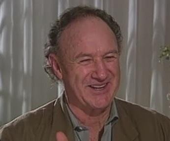 Gene Hackman w szczycie kariery aktorskiej, z intensywnym spojrzeniem, oddający jego wszechstronność i charyzmę.