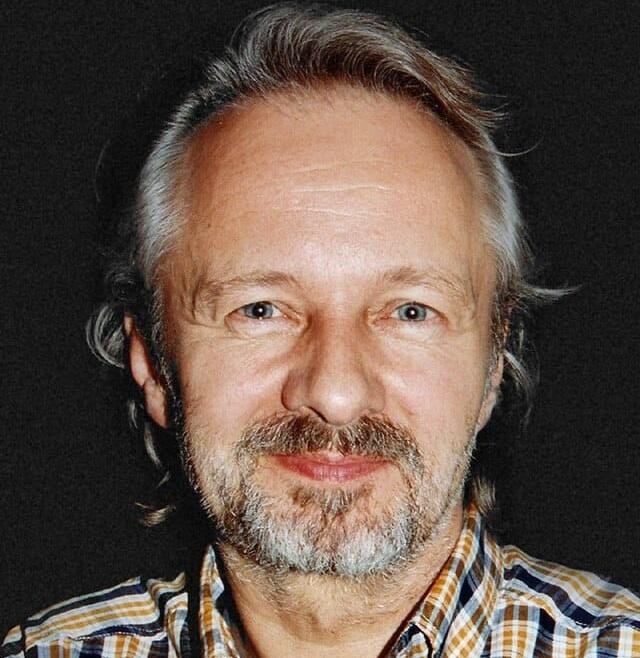 Krzysztof Stroiński w jednej ze swoich ikonicznych ról filmowych, z intensywnym wyrazem twarzy.