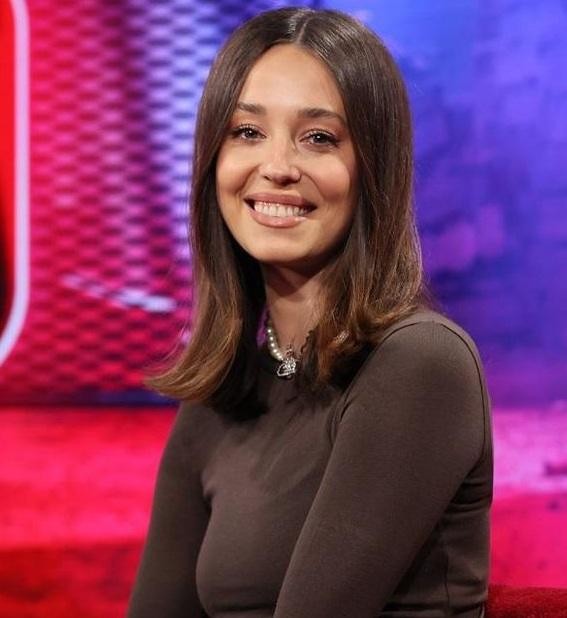 Izabella Krzan w nowoczesnym otoczeniu medialnym, z pewnym i zaangażowanym wyrazem twarzy, symbolizującym jej aktywność w różnych projektach.