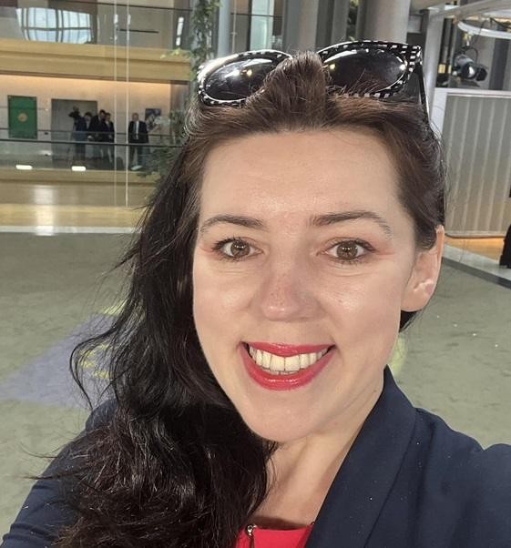 Dominika Ćosić aktywnie uczestnicząca w debacie lub prezentacji w Parlamencie Europejskim, z pewnym i zaangażowanym wyrazem twarzy.