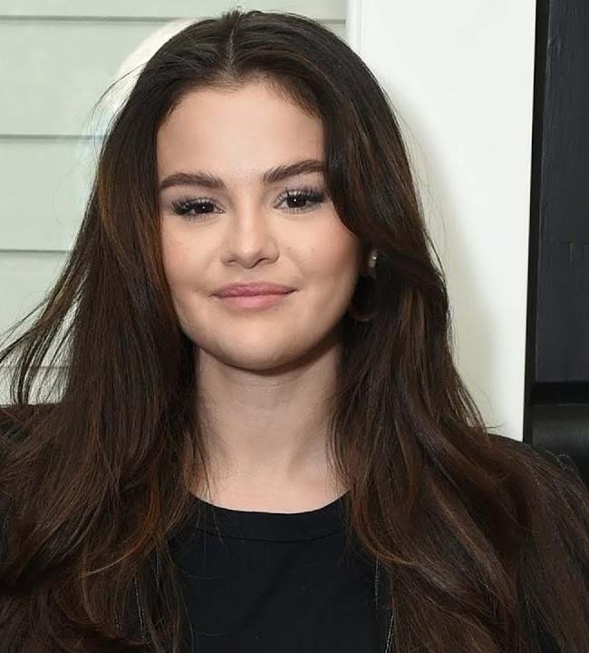 Selena Gomez trzymająca smartfon z otwartą aplikacją Instagram, promująca autentyczność i zdrowie psychiczne.